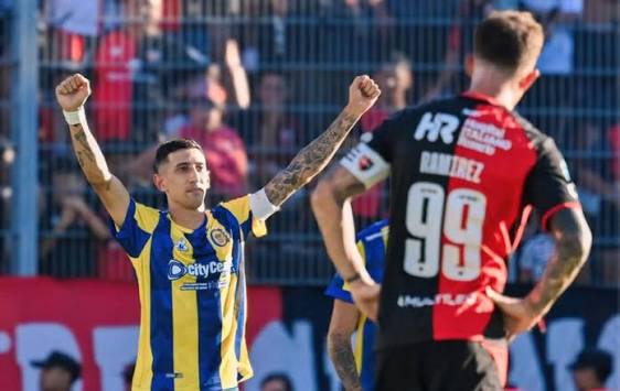 Jugador de Rosario Central festejando con los puños en alto frente a un jugador de Newell's