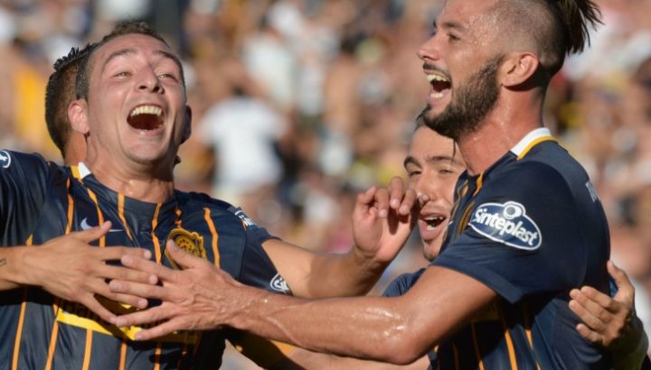 Dos jugadores de Rosario Central riendo y festejando un gol, con la camiseta de la época de Sinteplast