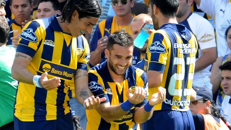 Tres jugadores de Rosario Central festejando un gol juntos, camiseta de la época de Sinteplast